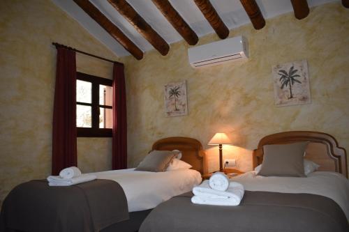 two beds sitting in a room with a window at Finca Durillo with private Pool in Cómpeta