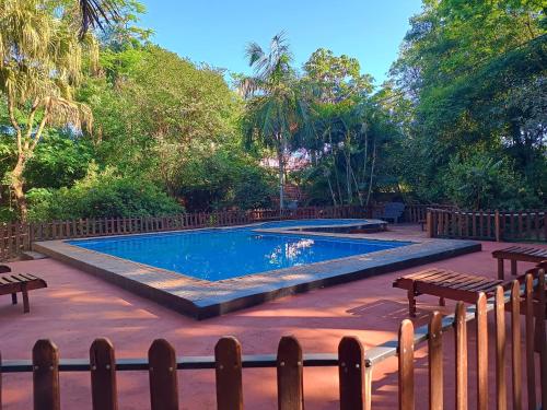 een zwembad in een tuin met een houten hek bij Ma-Ri Cabañas y Camping in Puerto Iguazú