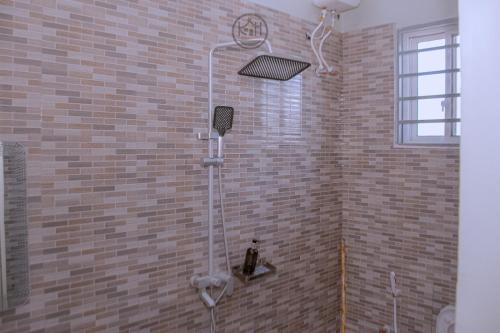 eine Dusche im Bad mit Ziegelwand in der Unterkunft Kwangu Homes Dodoma Collection in Dodoma