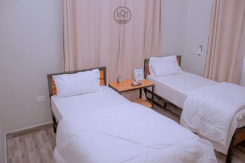 Zimmer mit 2 Betten und einem kleinen Tisch in der Unterkunft Kwangu Homes Dodoma Collection in Dodoma