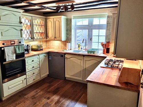 a kitchen with white cabinets and a wooden floor at Charming 3 bed kent Cottage in Chilham