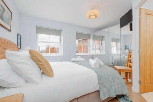 a white bedroom with a large bed with white pillows at Saxon Mews in Wareham