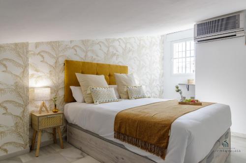 1 dormitorio con 1 cama grande y cabecero amarillo en Living4Malaga Sky Garden Duplex, en Málaga