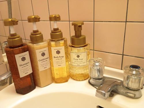 a bathroom sink with four bottles of oils on it at Hotel-澄Sumi in Naha
