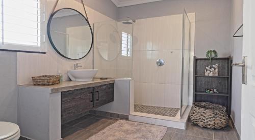 a bathroom with a sink and a shower with a mirror at Stripes & Sunsets Marloth Park in Marloth Park