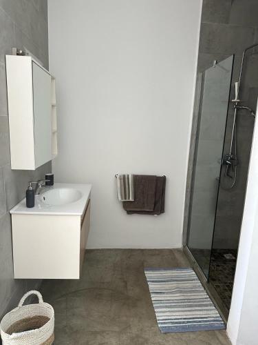 a white bathroom with a sink and a shower at Villa moderne face a la mer in Mahébourg