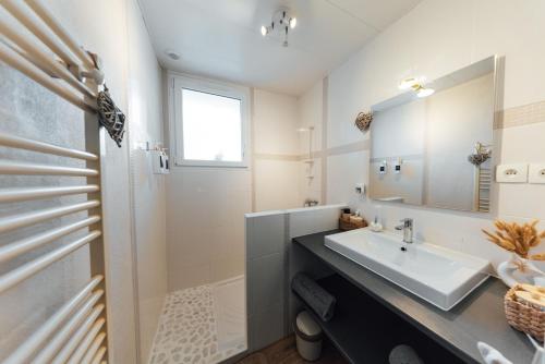 a white bathroom with a sink and a mirror at Instants Précieux - Love Room in Arvert