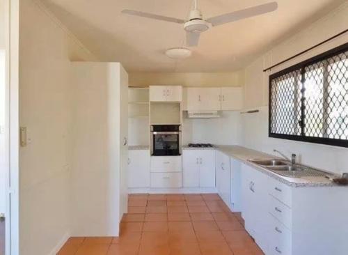a kitchen with white cabinets and a ceiling fan at Relax & Unwind, 5BR Home with Pool Near CBD in Garbutt Station
