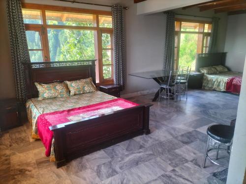 une chambre avec un lit, une table et des fenêtres dans l'établissement Ad cottage, à Nathia Gali