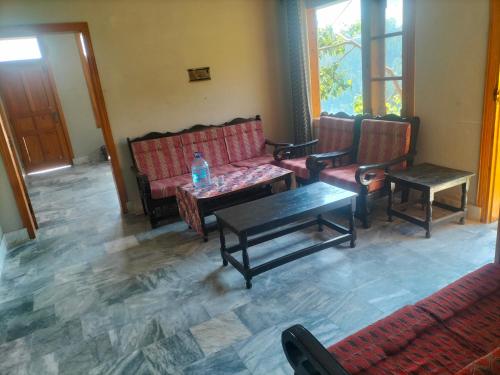 un salon avec des bancs et une table avec une bouteille d'eau dans l'établissement Ad cottage, à Nathia Gali