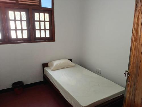 a small bed in a room with two windows at ANGEL VILLA , Place with nature and care in Midigama West