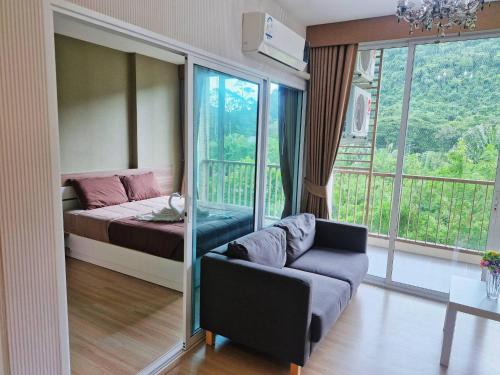 a room with a bed and a couch and a balcony at Baan Khaoyai by Chateau in Ban Tha Maprang