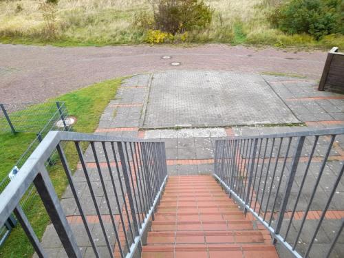 un escalier menant à un parking avec un portail dans l'établissement Moderne Ferienwohnung mit Balkon in Strandnähe, à Friedrichskoog