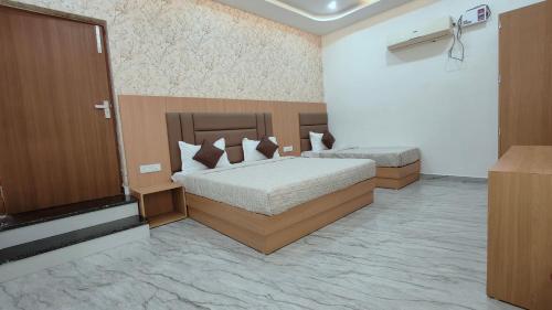 a bedroom with two beds and a television in it at Hotel Pilgrim walking distance From Golden Temple in Amritsar