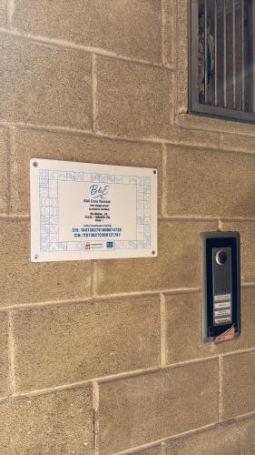 a sign on a brick wall with a pay phone at B&E Casa Vacanze in Taranto