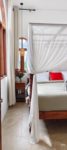 een slaapkamer met een wit bed met een hemelbed bij The Green Atelier Bali in Jimbaran