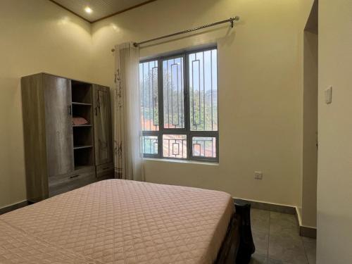 een slaapkamer met een bed en een raam bij Muraho Apartment in Kigali