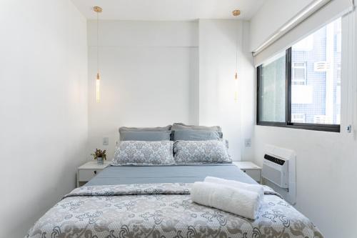 a white bedroom with a bed with blue sheets and a window at Place Beira Mar in Recife