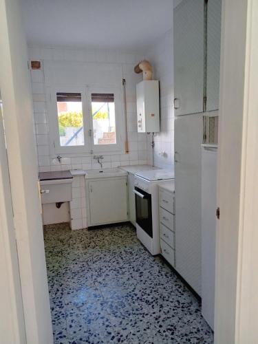 a small kitchen with white appliances and a window at Tamariua L2, apartamento cerca de la playa del Pas in Port de la Selva