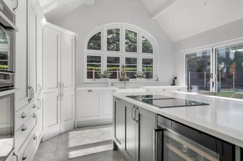 eine weiße Küche mit weißen Schränken und Fenstern in der Unterkunft Luxury Detached House in private grounds, with SPA in Weston upon Trent