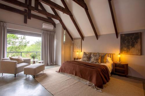 a bedroom with a bed and a chair and a window at House Nyala in Lydenburg