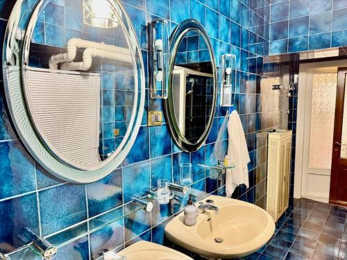 ein blau gefliestes Badezimmer mit einem Waschbecken und zwei Spiegeln in der Unterkunft Casa Juliett royal terraces in Turin