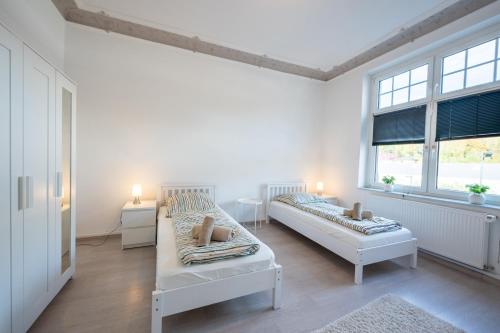a white room with two beds and two windows at HagenStay Eilpe 1 in Hagen