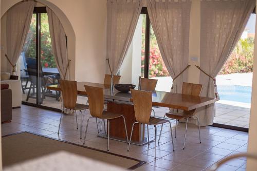 een eetkamer met een houten tafel en stoelen bij Villa Private Heated Pool Sea Views- Sleeps6 in Kouklia