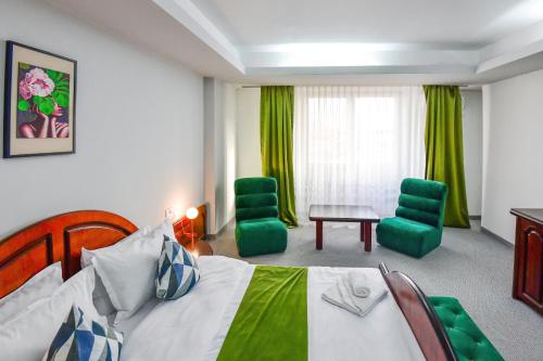 a hotel room with a bed and two green chairs at Royal by Euxin in Constanţa