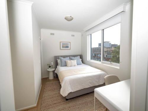 a white bedroom with a bed and a window at Villa Amari - A Sunny Tranquil Home in Melbourne