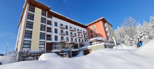 een gebouw met een berg sneeuw ervoor bij Hotel CROCUS in Štrbské Pleso