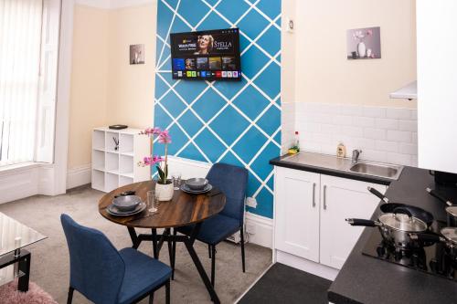 a kitchen with a wooden table and blue chairs at Rugby 1-BR Apt, Parking, City Centre, Sleeps 3 in Rugby