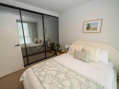 a bedroom with a white bed with a sliding glass door at Villa Solara - A Tranquil Light Filled Home in Melbourne