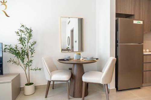a kitchen with a table and two chairs and a refrigerator at Stylish Yas Studio- Modern Urban Stay in Abu Dhabi