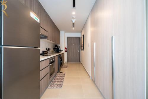 a kitchen with stainless steel appliances and a long hallway at Stylish Yas Studio- Modern Urban Stay in Abu Dhabi