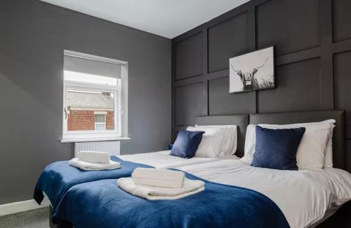 ein Schlafzimmer mit zwei Betten mit blauer Bettwäsche und einem Fenster in der Unterkunft Norris Stays - Sleeps 7 by M55 in Preston
