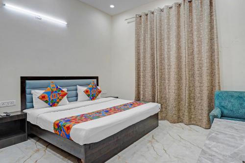 a bedroom with a bed and a blue chair at FabHotel Winsome Inn in Noida