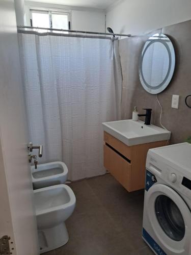 a bathroom with a toilet sink and a washing machine at Casa bella in Durazno