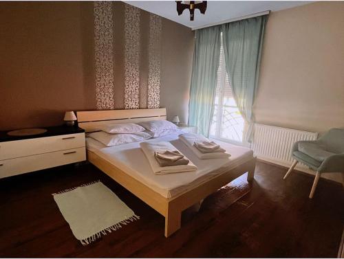 a bedroom with a bed and a window with a chair at Aqua Apartman in Pécs