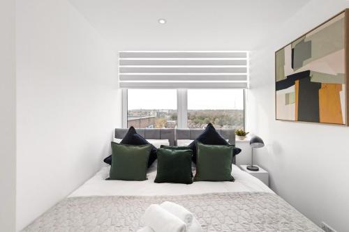 a bedroom with a bed with green pillows and a window at Sleek & Stylish Apartment in the Best Area in Beckenham