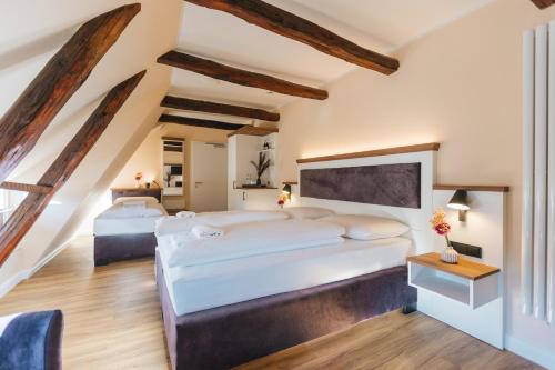 2 bedden in een zolderslaapkamer met houten balken bij Hotel Scheffler Lüneburg in Lüneburg