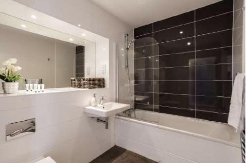 a white bathroom with a sink and a tub and a shower at The Luxurious Semi-Circle in Cambridge