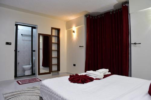 a bedroom with a bed with a red shower curtain at Araka Homes in Nakuru