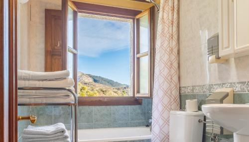 ein Badezimmer mit Fenster, Badewanne und Waschbecken in der Unterkunft Casa Collado Santo Tomás in Bodes