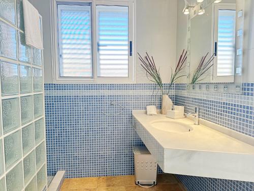 een blauw betegelde badkamer met een wastafel en een spiegel bij Villa en la Playa I 5BR I 5 WC I Piscina Privada in Sueca