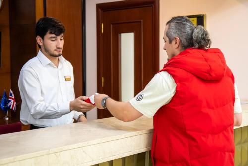 a man is handing a man something on a counter at Atropat Old City Hotel in Baku