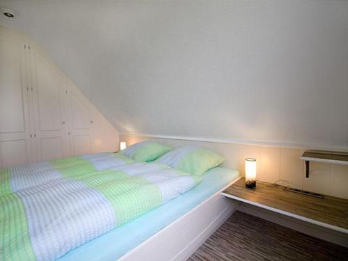 a bed with green and white sheets in a room at Ferienhaus Bleicken in Morsum