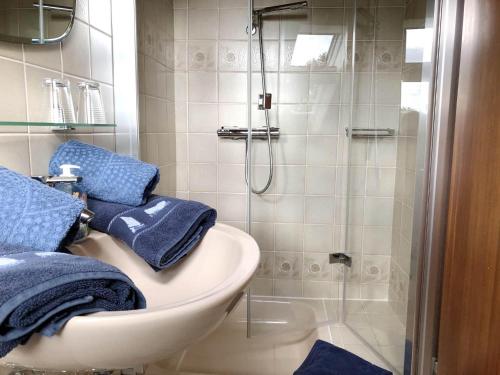 a bathroom with a sink and a shower with blue towels at Ferienhaus Bleicken in Morsum