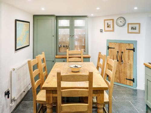 ein Esszimmer mit einem Holztisch und Stühlen in der Unterkunft Ivy Cottage - Tq4 in Boscastle