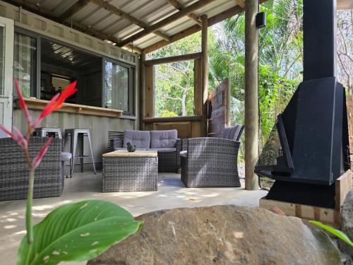 an outdoor patio with wicker furniture and a fireplace at Le Pavillon, at La Petite Ferme 2BRoom with private fireplace in Grand Sable